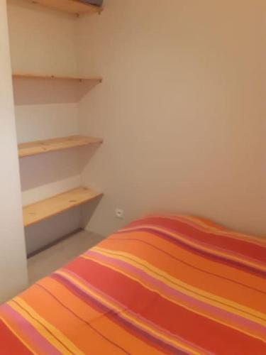 - une chambre avec un lit et une couverture rayée colorée dans l'établissement La cabane au fond du jardin, à Montrodat