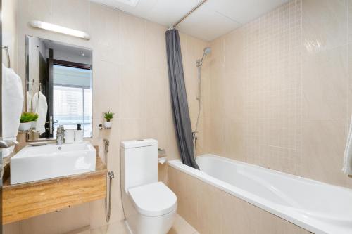 a bathroom with a toilet and a tub and a sink at White Sage - Gorgeous Apartment in JLT Near the Metro Station in Dubai