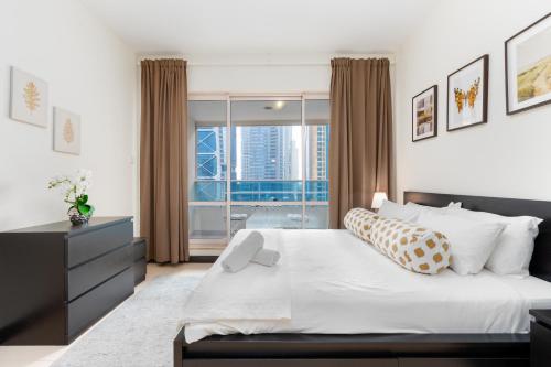 a bedroom with a bed and a large window at White Sage - Gorgeous Apartment in JLT Near the Metro Station in Dubai