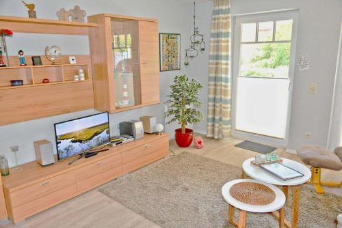 a living room with a flat screen tv sitting on a entertainment center at Zum Leuchtturm 10 Ferienwohnung Bi dat Blinkfuer in Westereck