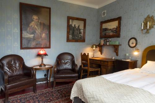 a bedroom with a bed and two chairs and a desk at Villa Wäring Husrum & Frukost in Varberg