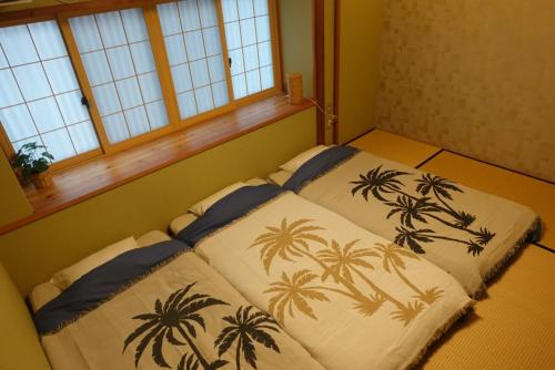 a bedroom with two beds with palm trees on them at ALOHADAYS Nishijin Guesthouse in Kyoto