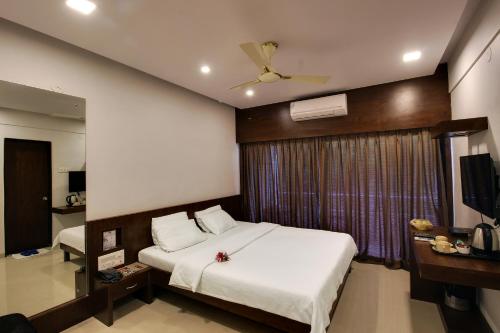 a hotel room with a bed and a television at Hotel Rama Heritage in Nashik