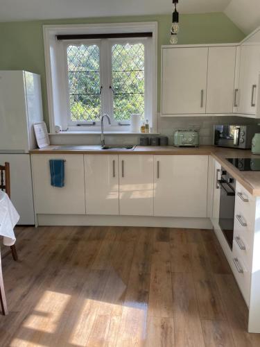 a kitchen with white cabinets and a sink and a window at 3 The Mews in Ryde