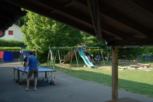 a man standing at a ping pong table in a park at Hostel Le Chandelier in Saint-Ursanne