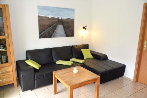 a living room with a black couch and a table at Zum Leuchtturm 10 Ferienwohnung Nr 05 in Westereck