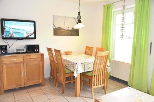 a dining room with a table and chairs and a television at Zum Leuchtturm 10 Ferienwohnung Nr 05 in Westereck