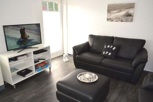 WestereckにあるZum Leuchtturm 10 Ferienwohnung Nr 07のリビングルーム(黒いソファ、テレビ付)