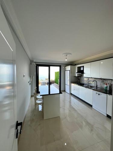 cocina grande con armarios blancos y mesa en Sea View Villa, en Trabzon
