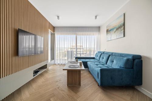a living room with a blue couch and a table at Solaris Darłówko Premium Emilia Strupiechowska in Darłowo