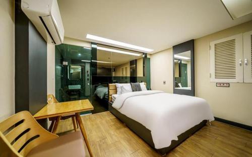 a bedroom with a large white bed and a table at Bulgwang 3S Hotel in Seoul
