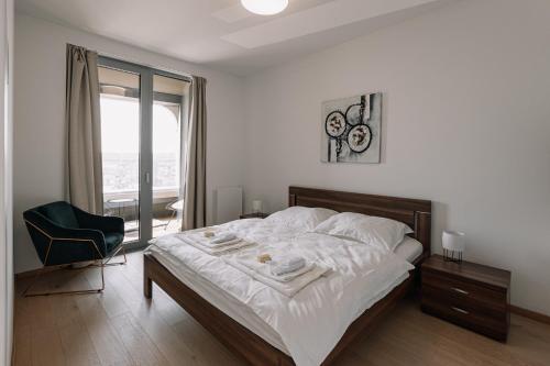 1 dormitorio con 1 cama, 1 silla y 1 ventana en SKAU Blue Residence in Sky Park 21 floor 2 tower Panoramic View Free Parking, en Bratislava