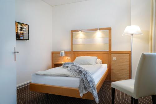 um quarto com uma cama com um espelho e uma cadeira em Park-Hotel am Rhein - Gesundheitshotel und Residenzen em Rheinfelden