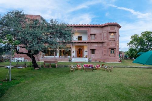 a large house with chairs and a table in the yard at Castle Oodeypore A Boutique stay Udaipur in Udaipur