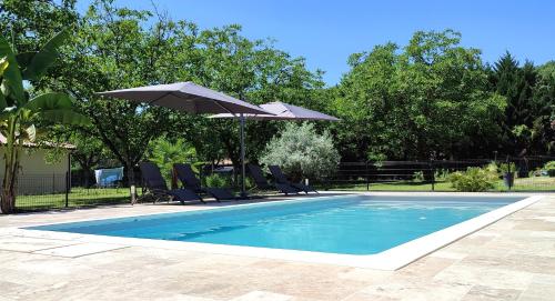 a swimming pool with chairs and an umbrella at Le 4 in Montignac