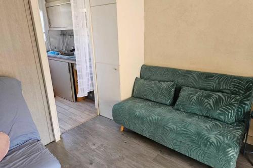 a green couch in a small room with a kitchen at Renovated apartment near the beach in Villers-sur-Mer