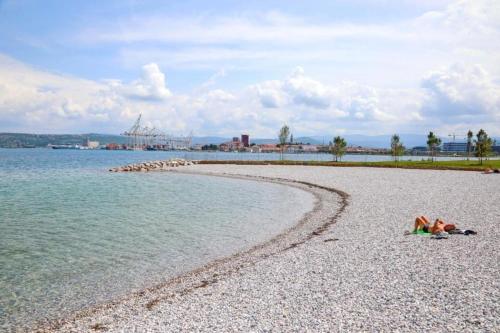 a person laying on a beach next to the water at AEGIDA BEACHFRONT apartment in Koper