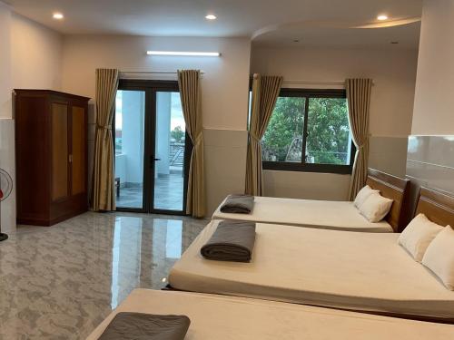 een slaapkamer met 2 bedden en een deur met ramen bij Hoàng Linh Hotel in Buon Ma Thuot