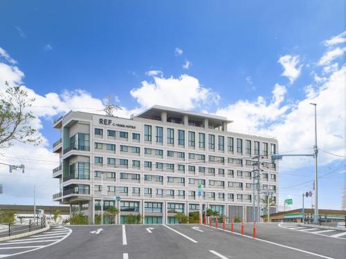 ein weißes Gebäude mit einem Parkplatz davor in der Unterkunft REF Okinawa Arena by VESSEL HOTEL in Okinawa