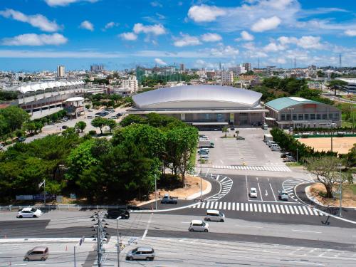 a city with a building and a street with cars at REF Okinawa Arena by VESSEL HOTELS in Okinawa City