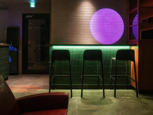 a green bar with three chairs in front of it at REF Okinawa Arena by VESSEL HOTELS in Okinawa City