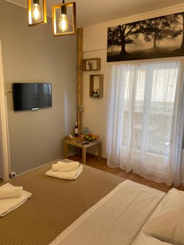 Schlafzimmer mit einem Bett, einem TV und einem Fenster in der Unterkunft MY HOME PERISTERI in Athen