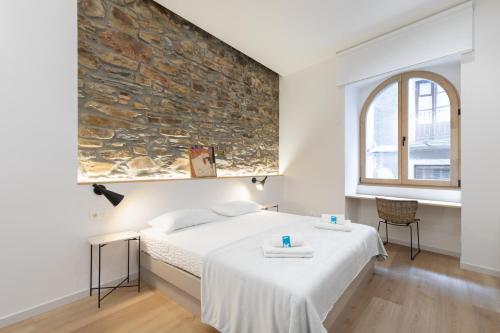 1 dormitorio con cama y pared de piedra en Zutabe - baskeyrentals, en Azpeitia