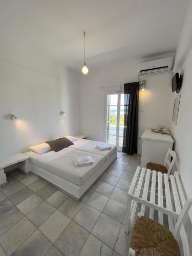 a white bedroom with a bed and a bench at Hotel Anezina in Drios