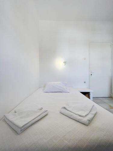 a white bed with two towels on top of it at Hotel Anezina in Drios