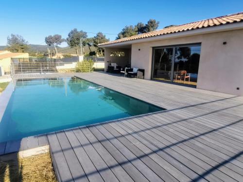 une piscine avec une terrasse en bois à côté d'une maison dans l'établissement Villa La Voile au Vent - Sur les collines de la Cadière d'Azur - Villa spacieuse, 4 chambres, climatisée avec piscine à débordement, Vue mer et collines, à Laouque