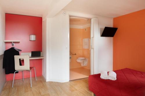 a bedroom with red walls and a bed and a bathroom at Premiere Classe La Ville Du Bois in La Ville-du-Bois