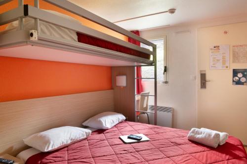 a bedroom with a bunk bed with a red bedspread at Premiere Classe La Ville Du Bois in La Ville-du-Bois