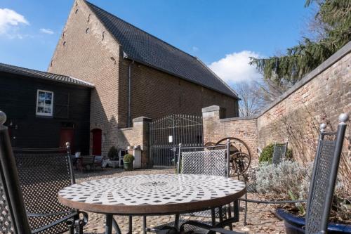 a patio with a table and chairs in front of a building at Meschermolen, overnachten in de schuur in Eijsden