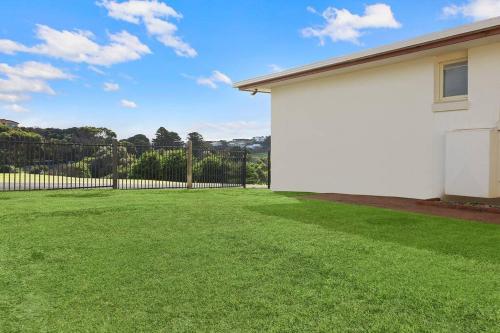 a large yard with a fence and a white house at Logans Beach Apartments - Greenviews in Warrnambool