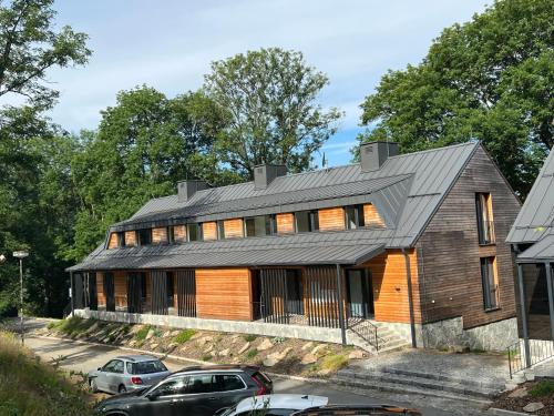 una gran casa de madera con coches aparcados frente a ella en Apartmán Borůvka en Železná Ruda