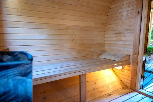 a wooden sauna with a bench in it at Domy z Bala - Domki ogrzewane - JACUZZI, SAUNA, lody, popcorn, ryba wedzona i ognisko w cenie! in Dziwnówek