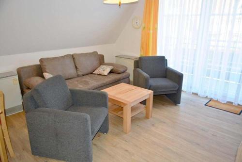 un soggiorno con divano e 2 sedie di Meene Menten Ferienwohnung Nr 04 a Süderhöft