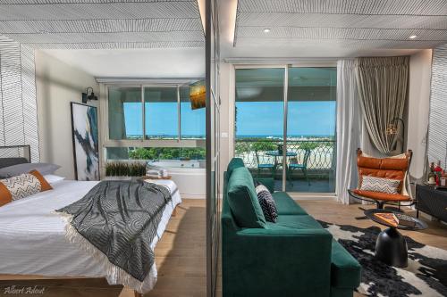 a bedroom with a bed and a couch and a balcony at Mina's luxury suite - panoramic sea view- קיסריה in Caesarea