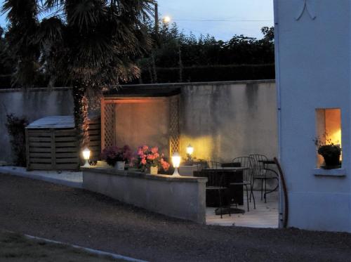 Un patio con mesa, sillas y luces. en Le Jardin Du Puits, en Longueville