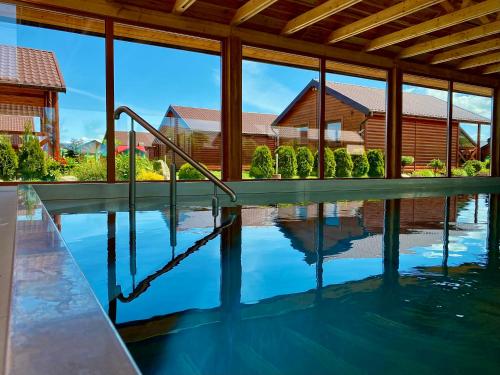 a swimming pool with a reflection of a house at Ostoja Maltańska in Jarosławiec