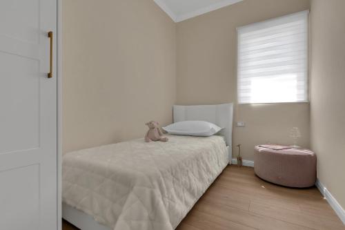 a white bedroom with a teddy bear sitting on a bed at Apartment Vranješ in Makarska
