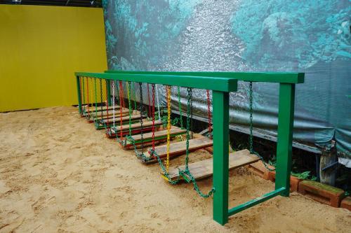 a green bench in the sand next to a wall at Kuruva Island Resort And Spa - By KABINI BREEZE in Mananthavady