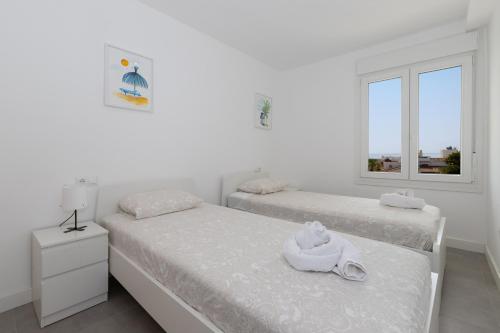 2 łóżka w białym pokoju z oknem w obiekcie Apartamento en Sotomar La Carihuela w mieście Torremolinos