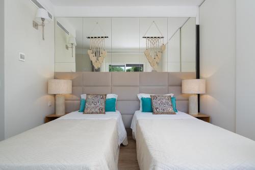 twee bedden in een kamer met spiegels en lampen bij Apartament Belharucas, 400 meters from beach in Albufeira