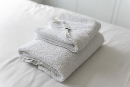una pila de toallas sentadas encima de una cama en Gertrude House - Spacious 3BR Bungalow in Nottingham, en Nottingham