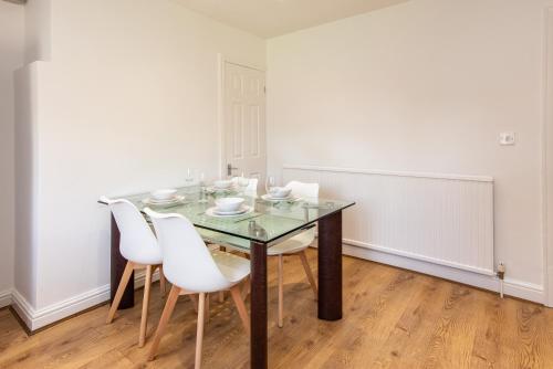 a dining room with a glass table and white chairs at Gertrude House - Spacious 3BR Bungalow in Nottingham in Nottingham