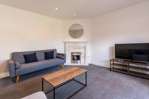 Una sala de estar con un sofá y un televisor. en Gertrude House - Spacious 3BR Bungalow in Nottingham, en Nottingham