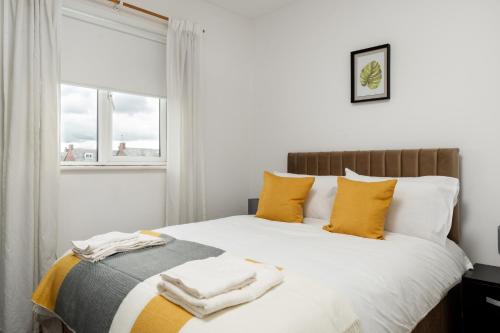 a bedroom with a bed with yellow pillows and a window at A delightful flat in Manchester. in Manchester