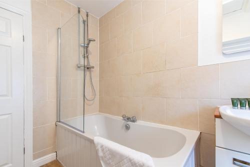 a bathroom with a shower and a tub and a sink at Gertrude House - Spacious 3BR Bungalow in Nottingham in Nottingham
