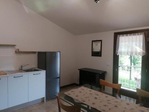 eine Küche mit einem Tisch und einem Kühlschrank aus Edelstahl in der Unterkunft Sweet Home Casa Vacanze il b&b in Songavazzo
